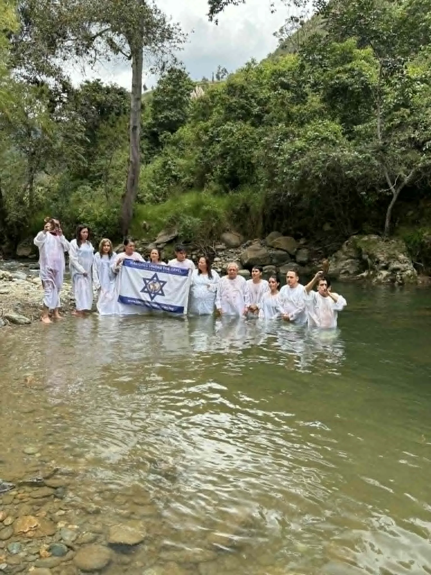 Bautizo grupal en el río con bandera de Israel